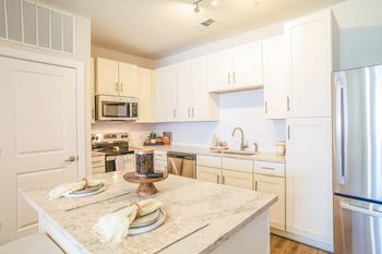 a kitchen with white cabinets and a marble counter top